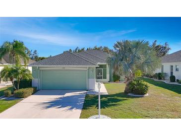 Single-story house with light green exterior, attached garage, and landscaped lawn at 1320 Misty Greens Dr, Sun City Center, FL 33573