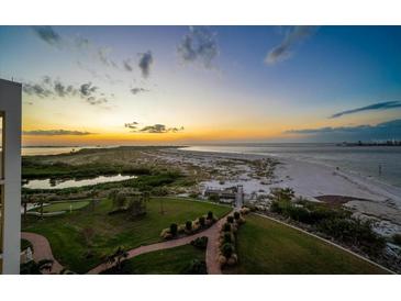 Beautiful sunset view of the beach, green grass, and walkway to the water at 800 Collany Rd # 605 & 606, Tierra Verde, FL 33715
