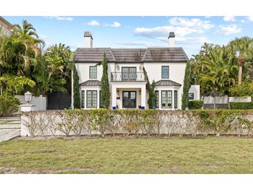 Two-story home with white exterior, dark roof, and manicured lawn at 140 Brightwaters Ne Blvd, St Petersburg, FL 33704