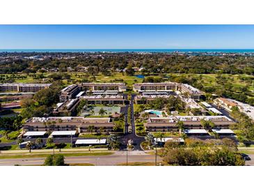 Aerial view of Villas de Golf community, showing buildings, pool, tennis court, and surrounding landscape at 12300 Vonn Rd # 9205, Largo, FL 33774
