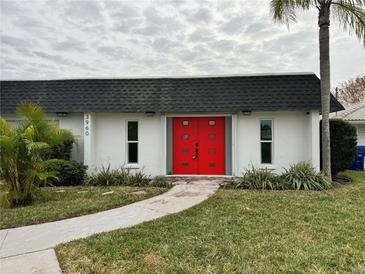 White single story home with a red front door and landscaped lawn at 3960 Headsail Dr, New Port Richey, FL 34652