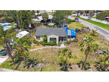Aerial view of a one-story home with a gray roof, lush greenery, and a classic vintage truck nearby at 8474 Tobay N Rd, St Petersburg, FL 33702