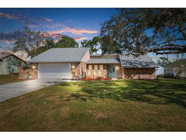 Brick house with a two-car garage, and a well-maintained lawn at 5592 Fairway Dr, Ridge Manor, FL 33523
