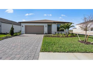 Charming one-story home with brick driveway, two car garage, and well-maintained front lawn at 2327 Candlebrook Path, North Port, FL 34289