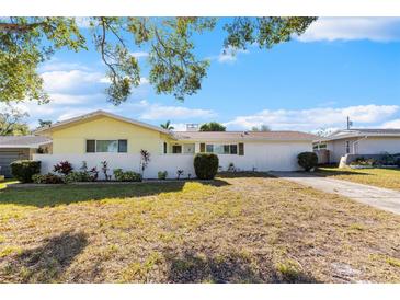 Ranch style home with white brick and yellow siding, landscaping, and a large yard at 1711 Patlin S Cir, Largo, FL 33770