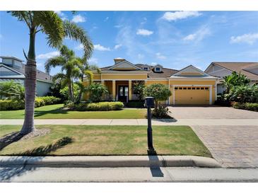 Charming yellow home with lush landscaping, brick driveway, and a well-maintained front lawn at 721 Manns Harbor Dr, Apollo Beach, FL 33572