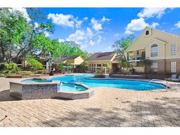 Inviting community pool with a spa and ample seating on a paved patio at 8609 Mallard Reserve Dr # 202, Tampa, FL 33614