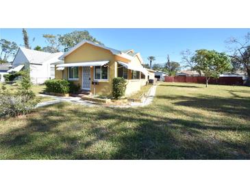 Yellow house with a green roof, awnings, and a yard at 1360 Prescott S St, St Petersburg, FL 33712