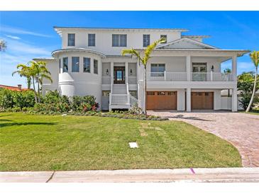 Stunning multi-story white home with lush landscaping, brick driveway, and attached garages, blending luxury and curb appeal at 6189 Leeland S St, St Petersburg, FL 33715