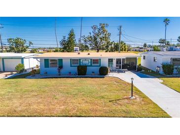 White single story home with teal accents, landscaped lawn, and driveway at 805 Augusta Dr, Sun City Center, FL 33573