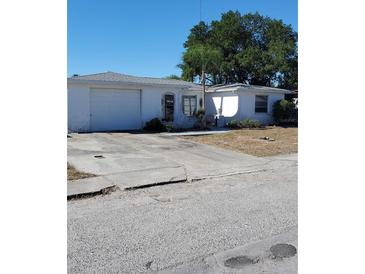 Ranch style home with a single car garage and mature landscaping at 1147 Viking Dr, Holiday, FL 34691