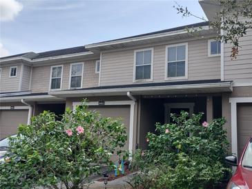 Tan two-story townhome with a two-car garage and landscaping at 8003 Bally Money Rd, Tampa, FL 33610