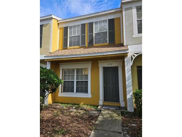 Two-story yellow townhome with gray door and landscaping at 1252 Costa Mesa Dr, Wesley Chapel, FL 33543