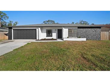 Updated single-story home with a modern gray and white exterior, stone accents, and a spacious lawn at 16515 Forestlake Dr, Tampa, FL 33624