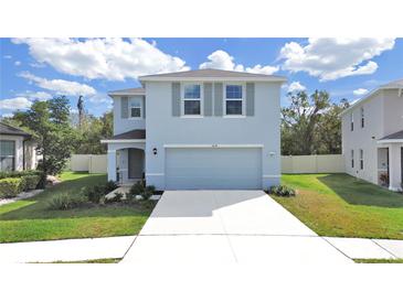 Two-story house with light blue exterior, two-car garage, and landscaping at 5018 Bella Armonia Cir, Wimauma, FL 33598