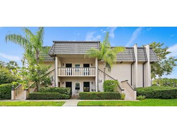 Two-story condo building with gray tile roofs, lush landscaping, and a paved walkway at 1403 Cordova Grn, Seminole, FL 33777