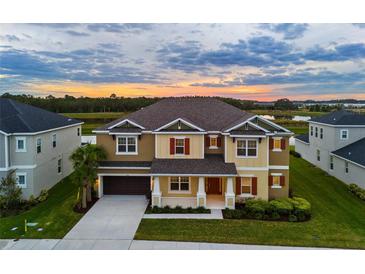 Two-story house with a neutral color scheme and a three-car garage, set against a scenic sunset backdrop at 33746 Castaway Loop, Wesley Chapel, FL 33543