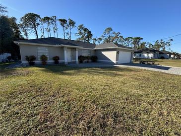 One-story home with a gray exterior, a two-car garage, and a well-manicured lawn at 3087 Seth Rd, North Port, FL 34288