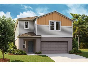 Two-story home with gray and orange siding, two-car garage, and landscaping at 12161 Cattleside Dr, Riverview, FL 33579