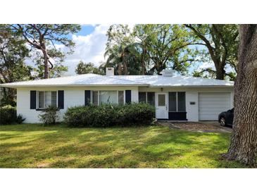 White single story home with metal roof, mature landscaping, and a two car garage at 11523 Forest Hills Dr, Tampa, FL 33612