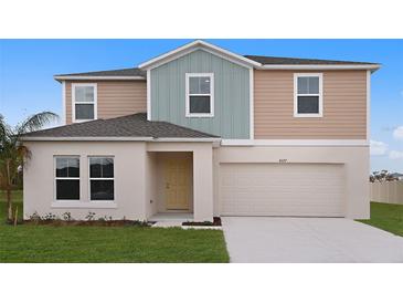 Two-story house with light beige and teal siding, two-car garage, and landscaped lawn at 14711 Summer Branch Dr, Lithia, FL 33547