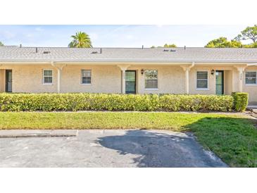 Front view of a light yellow building with a hedge and grassy lawn at 2465 Northside Dr # 205, Clearwater, FL 33761