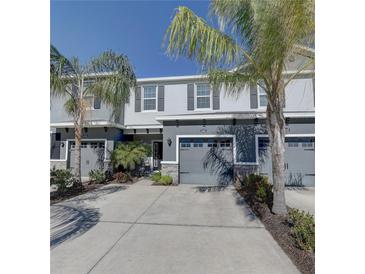 Two-story townhome with gray siding, two-car garage, and palm trees at 6436 Boxgrove Dr, Sarasota, FL 34240