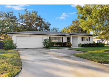 Ranch-style home with a white exterior, attached garage, and well-manicured lawn at 806 Brookside Dr, Clearwater, FL 33764