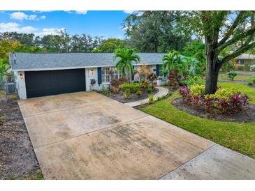 Ranch style home with landscaped yard, driveway, and attached garage at 4918 N River Shore Dr, Tampa, FL 33603