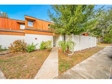 Exterior view of a townhome with wood siding, walkway, and fenced yard at 2062 Sunset Point Rd # 65, Clearwater, FL 33765