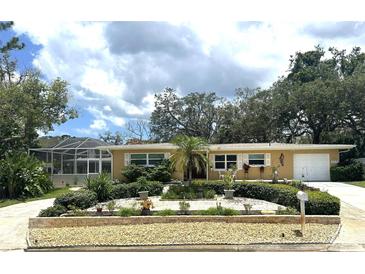 Charming single-story home with well-manicured landscaping, a screened porch and a freshly painted facade at 209 Westwinds Dr, Palm Harbor, FL 34683