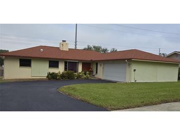 House exterior featuring a red roof and attached garage at 855 Pinewood W Ter, Palm Harbor, FL 34683