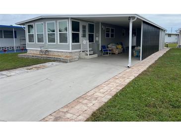 Mobile home with carport, paved driveway, and landscaped yard at 13225 101St St # 166, Largo, FL 33773