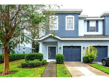 Two-story townhome with blue exterior, two-car garage, and landscaped front yard at 4445 Amberly Oaks Ct, Tampa, FL 33614