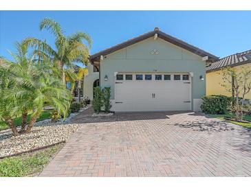 Single-story home with light green exterior, a two-car garage, and a brick driveway at 710 16Th E Ave, Palmetto, FL 34221