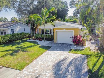 Attractive yellow house with landscaped yard, paver driveway, and two-car garage at 1710 Shore Acres Ne Blvd, St Petersburg, FL 33703