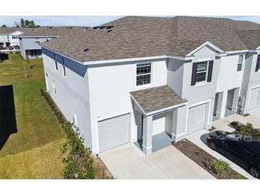 Exterior view of a two-story townhome with gray siding, attached garage, and a paved driveway at 33055 Tulip Petal Ln, Wesley Chapel, FL 33545