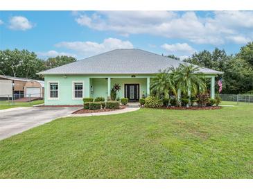 Light green house with covered porch, landscaping, and large backyard at 13810 Walden Sheffield Rd, Dover, FL 33527