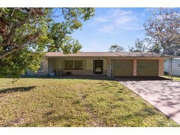 Ranch-style home with a double garage, situated on a grassy lot with mature trees at 4148 Arrowhead Ave, Spring Hill, FL 34606