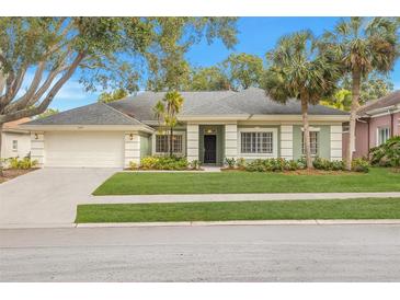 One-story home with a green facade, gray roof, and nicely landscaped lawn at 3077 Regal Oaks Blvd, Palm Harbor, FL 34684