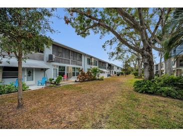 Exterior view of condominium units with private patios overlooking the expansive, well-maintained backyard at 4152 55 N Way # 1030, Kenneth City, FL 33709