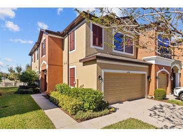 Tan two story townhome with brown shutters and a two car garage at 11546 Crowned Sparrow Ln, Tampa, FL 33626