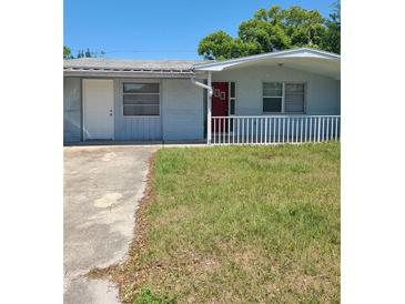 Ranch-style home with red front door, white railing, and a grassy yard at 4233 Darlington Rd, Holiday, FL 34691