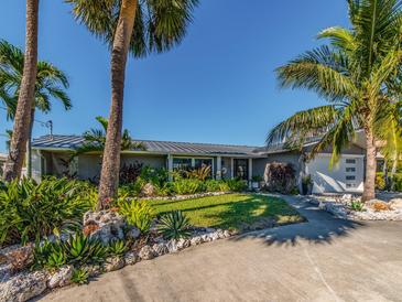 Tropical landscaping surrounds this charming Florida home, featuring a metal roof and modern design at 54 Midway Is, Clearwater Beach, FL 33767