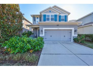Gray two-story house with teal shutters, two-car garage, and landscaped front yard at 6337 Waves End Pl, Apollo Beach, FL 33572