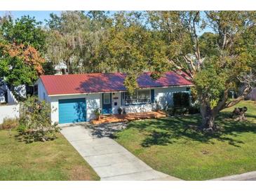 Charming single story home with a red metal roof, teal garage door, and well manicured lawn at 5301 16Th N Ave, St Petersburg, FL 33710