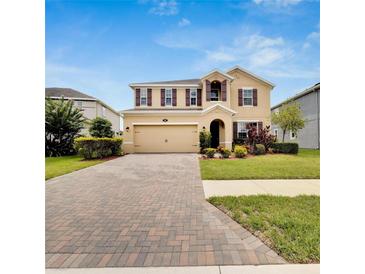 Two-story house with a brick driveway and landscaping at 1192 Multiflora Loop, Lutz, FL 33558
