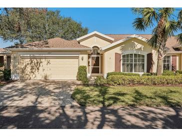 House exterior featuring a two-car garage and well-manicured landscaping at 2217 Brookfield Greens Cir, Sun City Center, FL 33573