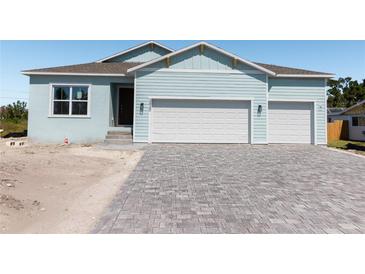Charming light blue home featuring a spacious two-car garage and a stylish paved driveway at 3430 Sarto Ln, Rotonda West, FL 33947
