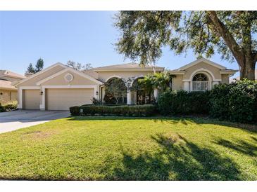 Beautiful home with 3-car garage, lush landscaping, and a well-manicured lawn at 4324 Auston Way, Palm Harbor, FL 34685